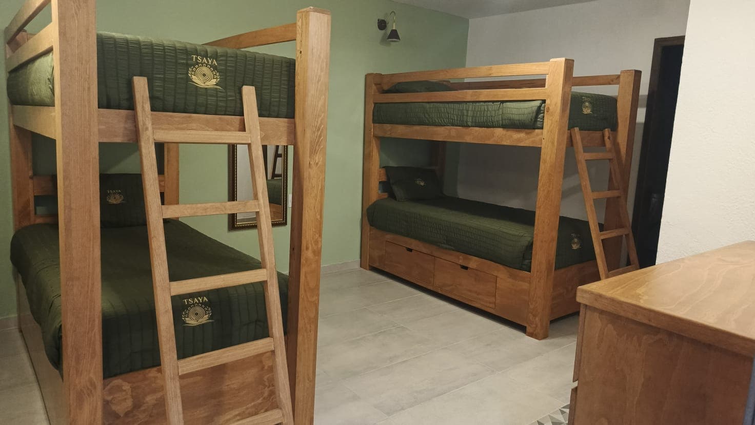 Habitación compartida de TSAYA con literas de madera y ropa de cama institucional