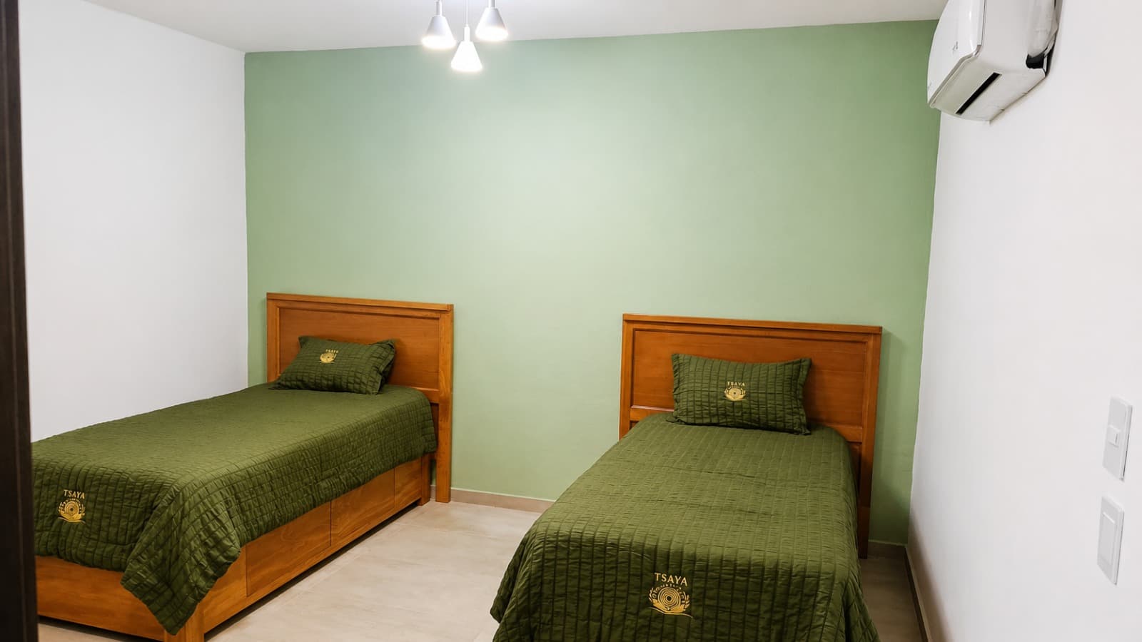 Habitación doble de TSAYA con camas individuales y ropa de cama institucional